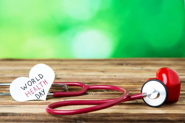 Texto Día Mundial de la Salud con estetoscopio y corazón rojo en ba verde — Foto de Stock