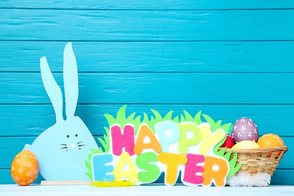 Huevos coloridos con conejo de madera y texto Feliz Pascua en azul b — Foto de Stock