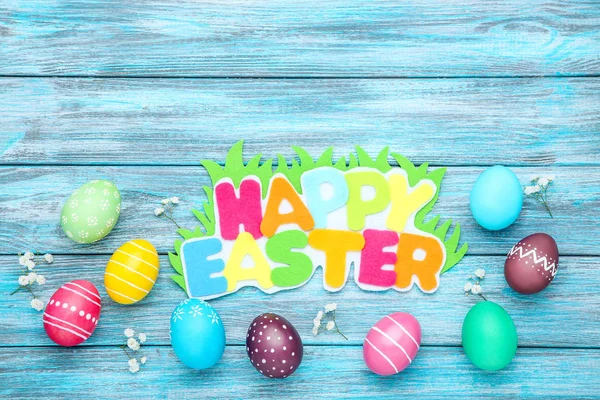 Colorful eggs with flowers and text Happy Easter on blue wooden — Stock Photo, Image