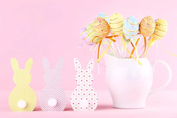 Coelhos de papel com ovos de Páscoa em fundo rosa — Fotografia de Stock