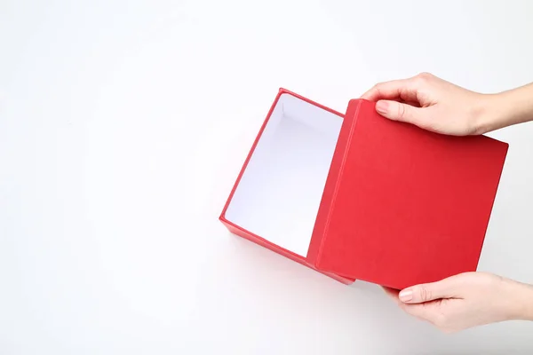 Руки женщины открывают красную подарочную коробку на белом фоне — стоковое фото
