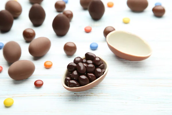 Œufs de Pâques en chocolat avec des bonbons colorés sur une table en bois — Photo