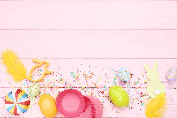 Ovos de Páscoa com coelhos e confetes coloridos em ta de madeira rosa — Fotografia de Stock
