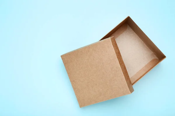 Open brown gift box on blue background — Stock Photo, Image