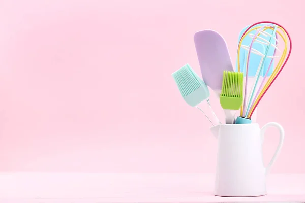 Kitchen utensils in white jar on pink background — Stock Photo, Image