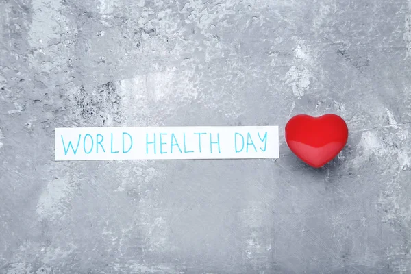 Text World Health Day with red heart on grey background