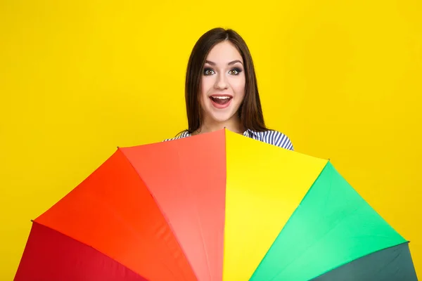 Ung flicka med färgglada paraply på gul bakgrund — Stockfoto