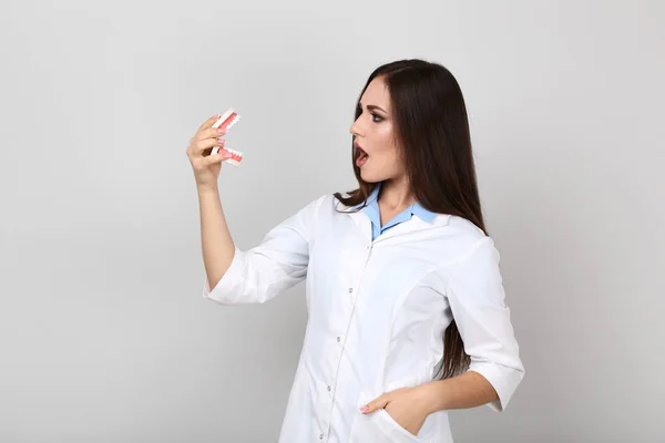 Joven médico sosteniendo modelo de dientes sobre fondo gris —  Fotos de Stock