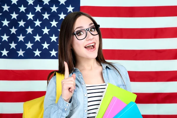 Joven estudiante con mochila y libros sobre fondos de bandera estadounidense — Foto de Stock