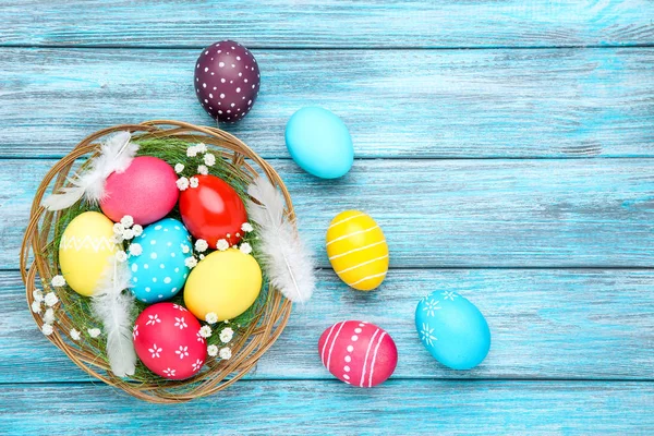 Oeufs de Pâques colorés dans le panier avec des fleurs de gypsophila et feath — Photo