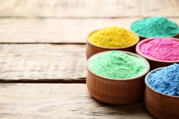 Polvo de holi colorido en cuencos sobre mesa de madera marrón — Foto de Stock