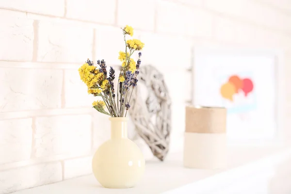 Bloemen in vaas op de witte open haard — Stockfoto