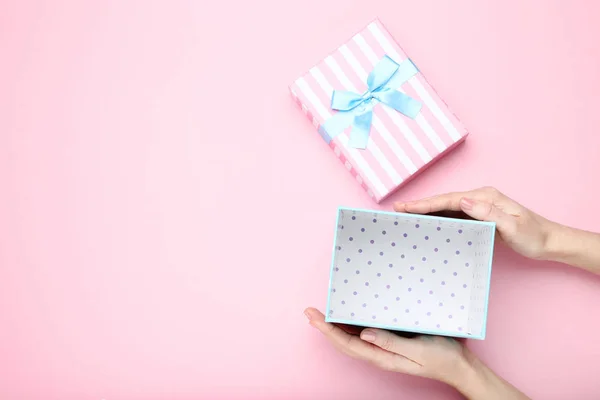 Manos femeninas sosteniendo caja de regalo sobre fondo rosa — Foto de Stock