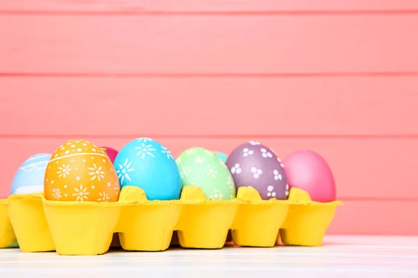 Uova di Pasqua colorate in scatola di cartone su tavolo di legno — Foto Stock