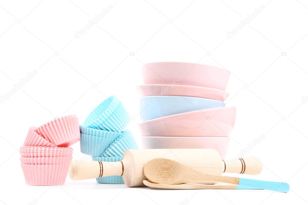 Cupcake cases with bowls and utensils on white background