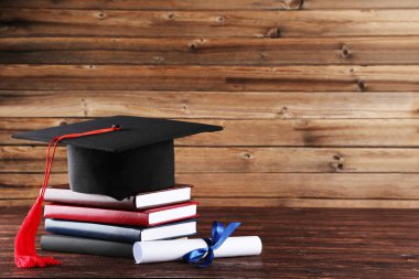 Diploma ve kahverengi ahşap t üzerinde kitap yığını ile mezuniyet kap