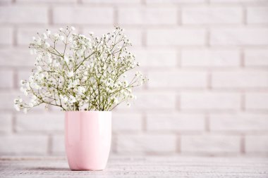 Tuğla duvar arka planda pembe fincan beyaz Gypsophila çiçekler