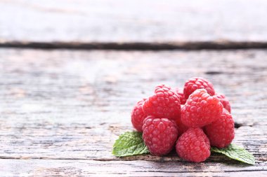 Gri ahşap masada yeşil yapraklarla olgun ahududu