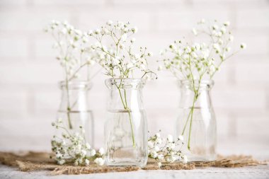Beyaz Gypsophila çiçekler cam şişeler üzerinde tuğla duvar backgrou