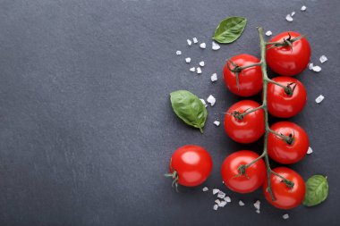 Siyah arka planda fesleğen yaprakları ve baharatlar ile kiraz domatesleri
