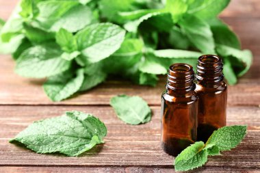 Kahverengi ahşap masa üzerinde esansiyel yağ ile nane yaprakları