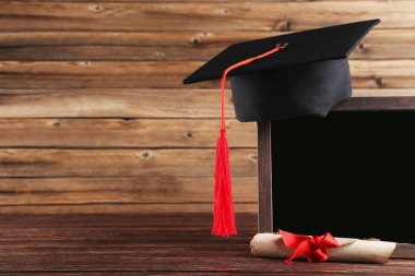 Diploma ve kahverengi ahşap TABL üzerinde boş çerçeve ile mezuniyet kap