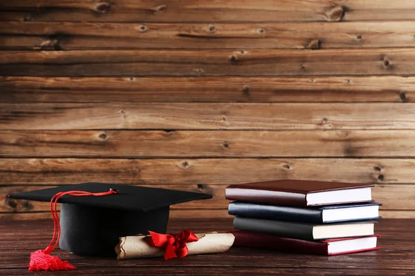 Tapa de graduación con diploma y pila de libros en t de madera marrón — Foto de Stock