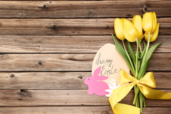 Жовті тюльпани з паперовою кролика і текстом щасливої Пасхи на коричневий w — стокове фото
