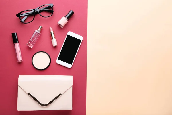 Bolso con cosméticos, smartphone y gafas en respaldo colorido —  Fotos de Stock