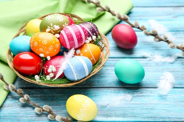 Ovos de páscoa coloridos em cesta com flores de gypsophila e feath — Fotografia de Stock