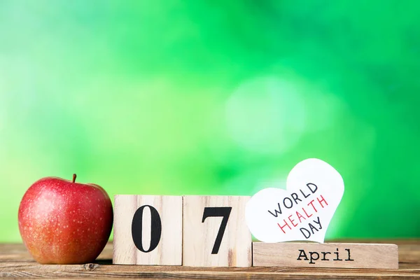 Text World Health Day with red apple and cube calendar on green