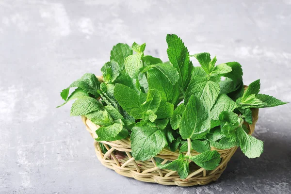 Mint leafs dalam keranjang di atas meja kayu abu-abu — Stok Foto