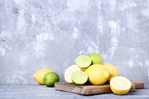 Zralé citrony a limetky na šedý dřevěný stůl — Stock fotografie