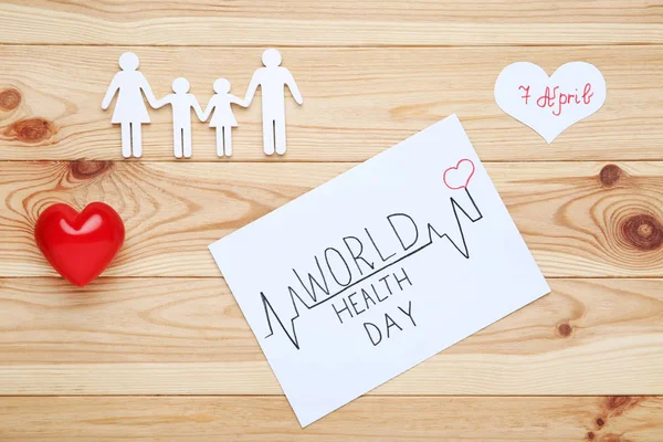 Text World Health Day with family figure and red heart on wooden