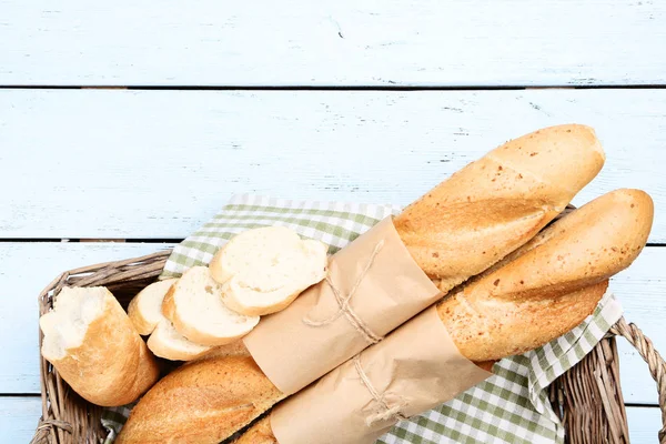 Baguettes frescos con servilleta en cesta sobre mesa de madera — Foto de Stock