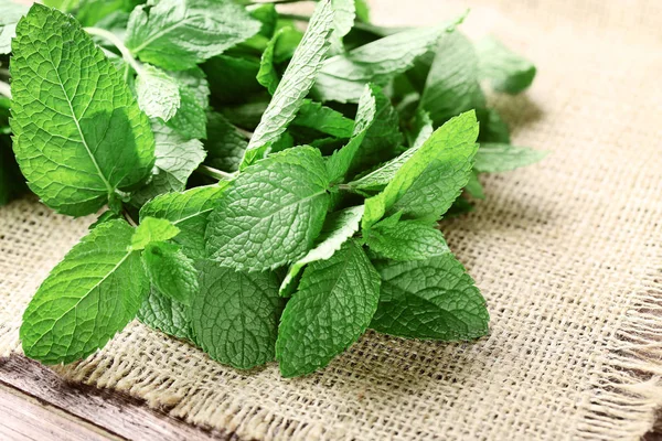 Mint leafs dengan kain karung di atas meja kayu — Stok Foto