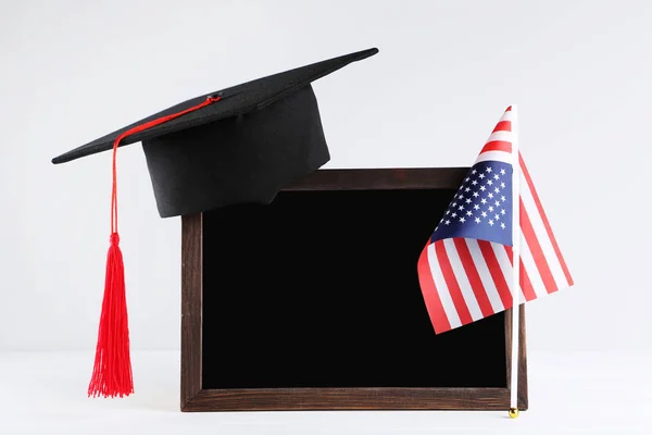 Gorra de graduación con marco en blanco y bandera americana sobre fondo gris — Foto de Stock