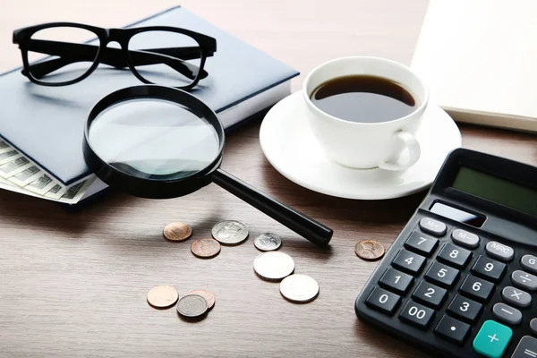 Pièces avec calculatrice, ordinateur portable et tasse de café sur table en bois — Photo