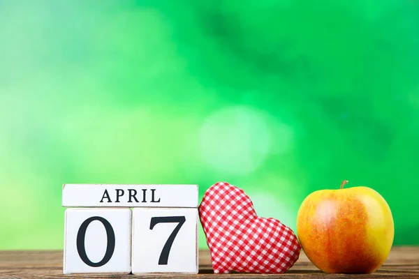 7 aprile sul calendario a cubetti con mela e cuore di tessuto su gr — Foto Stock