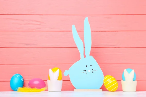 Œufs de Pâques colorés avec lapin en bois sur la couleur corail retour — Photo