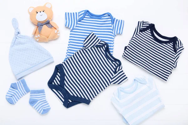 Bayi pakaian dengan mainan beruang lembut di latar belakang putih — Stok Foto