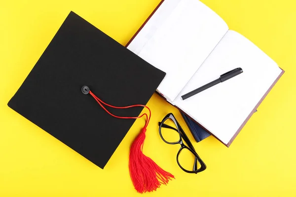 Tappo graduato con blocco note, penna e occhiali sul retro giallo — Foto Stock