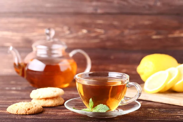 Taza de té con galletas y hojas de menta sobre mesa de madera — Foto de Stock