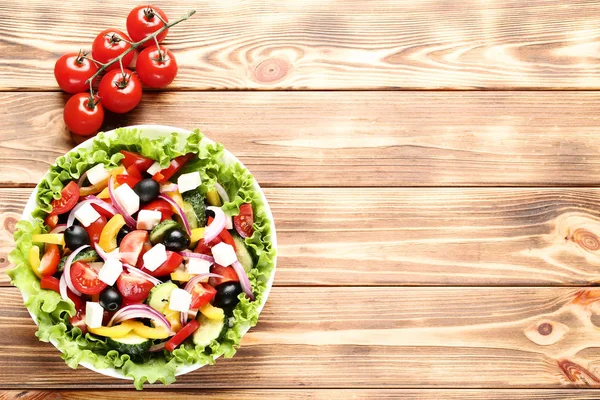 Groente salade in een kom met tomaten op bruine houten tafel — Stockfoto