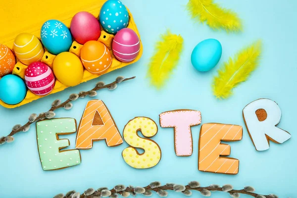 Барвисті яйця зі словом Великдень і гілки верби на синьому фоні — стокове фото