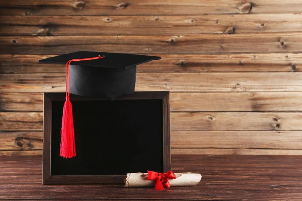 Tapa de graduación con diploma y marco en blanco en tabl de madera marrón — Foto de Stock
