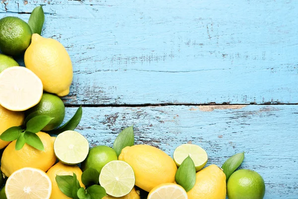 Citróny a citrusy se zelenými lístečky na modré dřevěný stůl — Stock fotografie