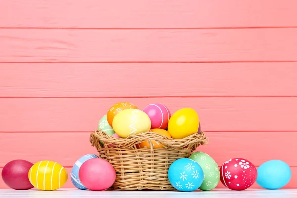 Œufs de Pâques colorés dans le panier sur fond en bois — Photo