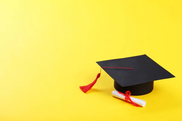 Tapa de graduación con diploma sobre fondo amarillo — Foto de Stock