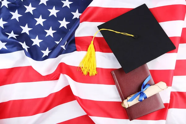 Gorra de graduación con diploma y bloc de notas en backgro bandera americana Fotos de stock libres de derechos